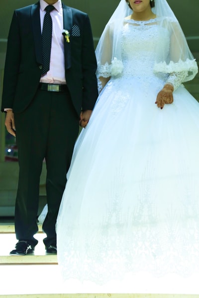 bride and groom standing on white wedding dress